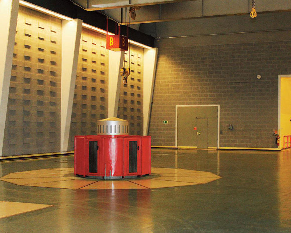 Interior view of machine room with the top of one generating unit visible above the floor